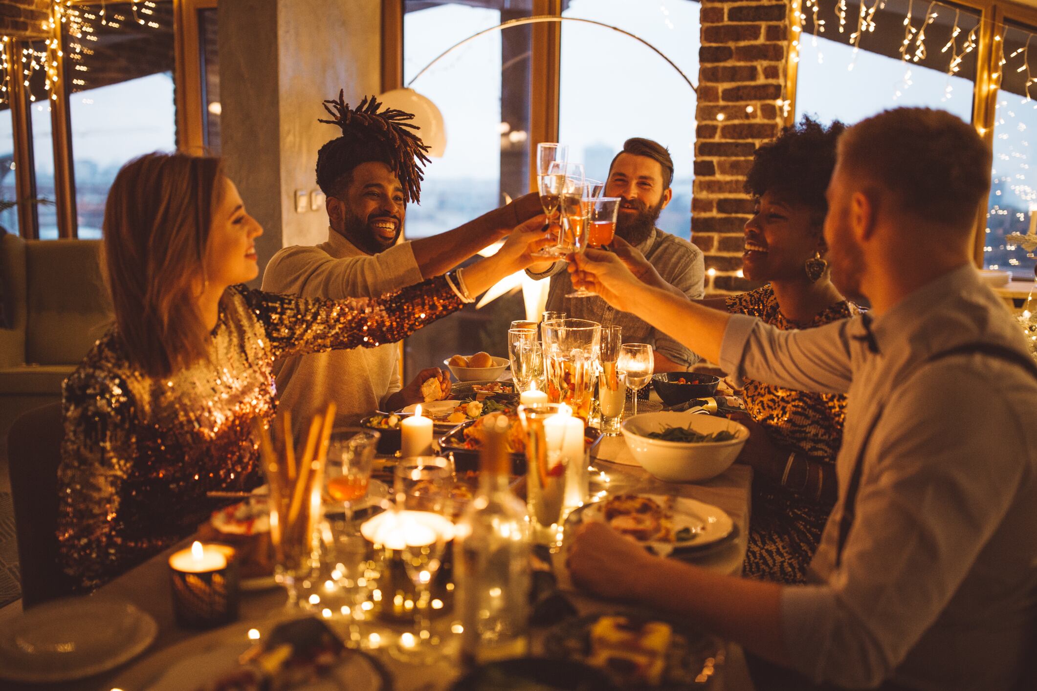 Multi ethnic group of friends having new year dinner party, everyone enjoying in food and drink