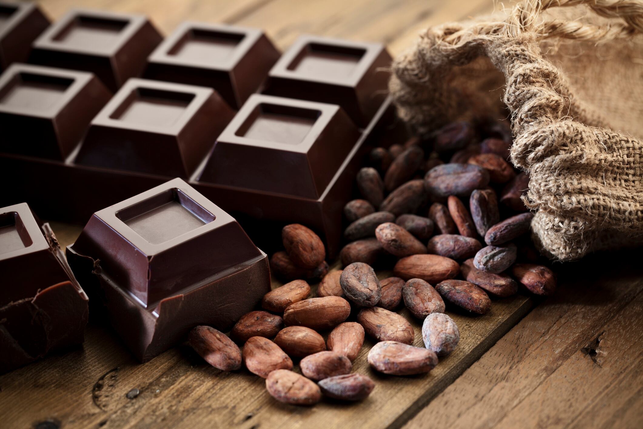 Dark chocolate with cocoa beans on wooden table