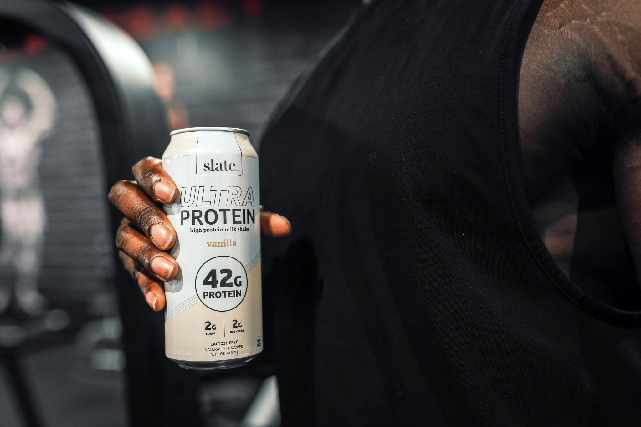 african american person holding a can of protein shake in a gym