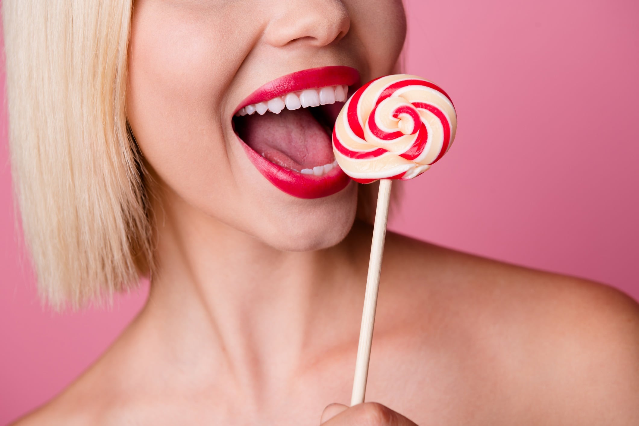 Cropped photo of pretty excited lady nude shoulders biting stick caramel isolated pink color background.