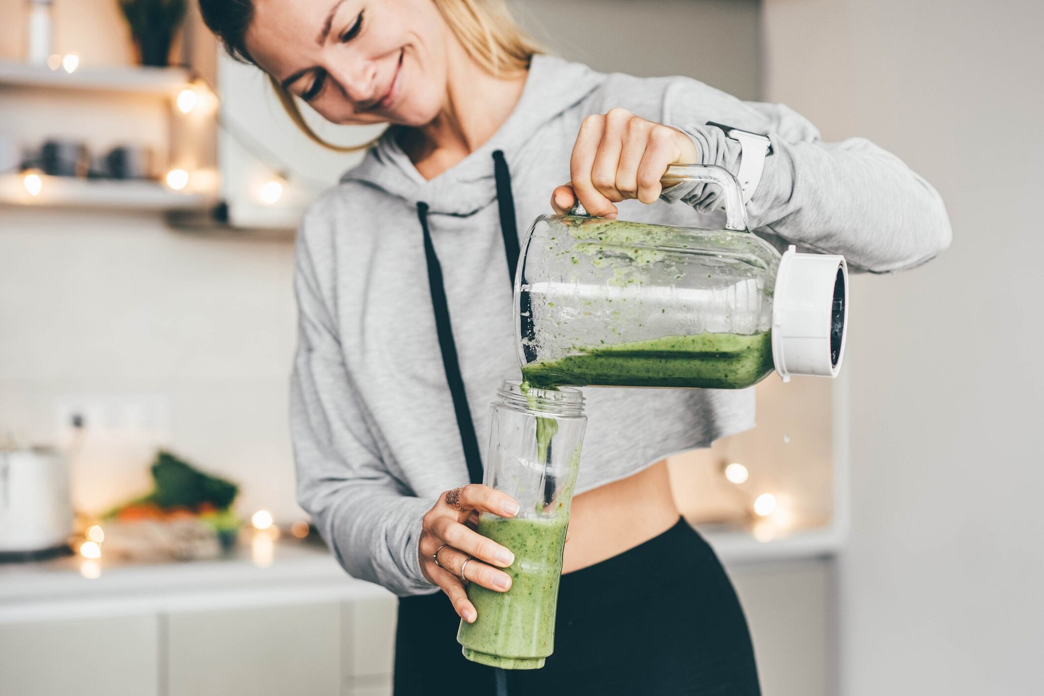 Woman Making Detox Smoothie At Home. Woman pouring smoothie to glass. healthy food concept