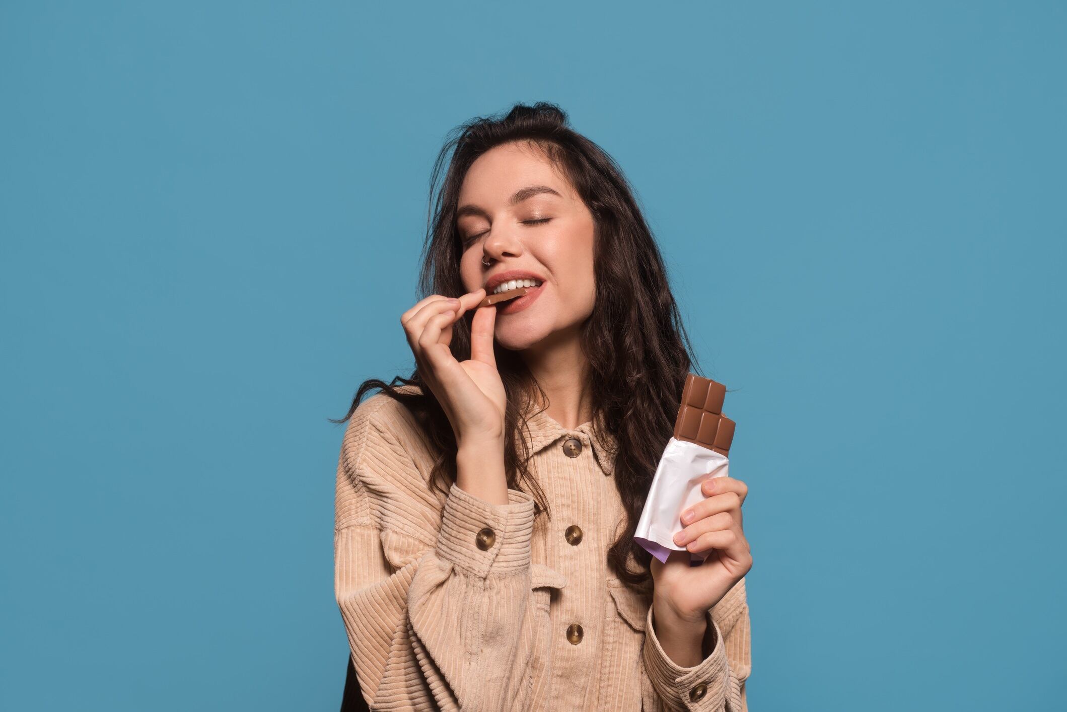 Woman eating chocolate bar with closed eyes