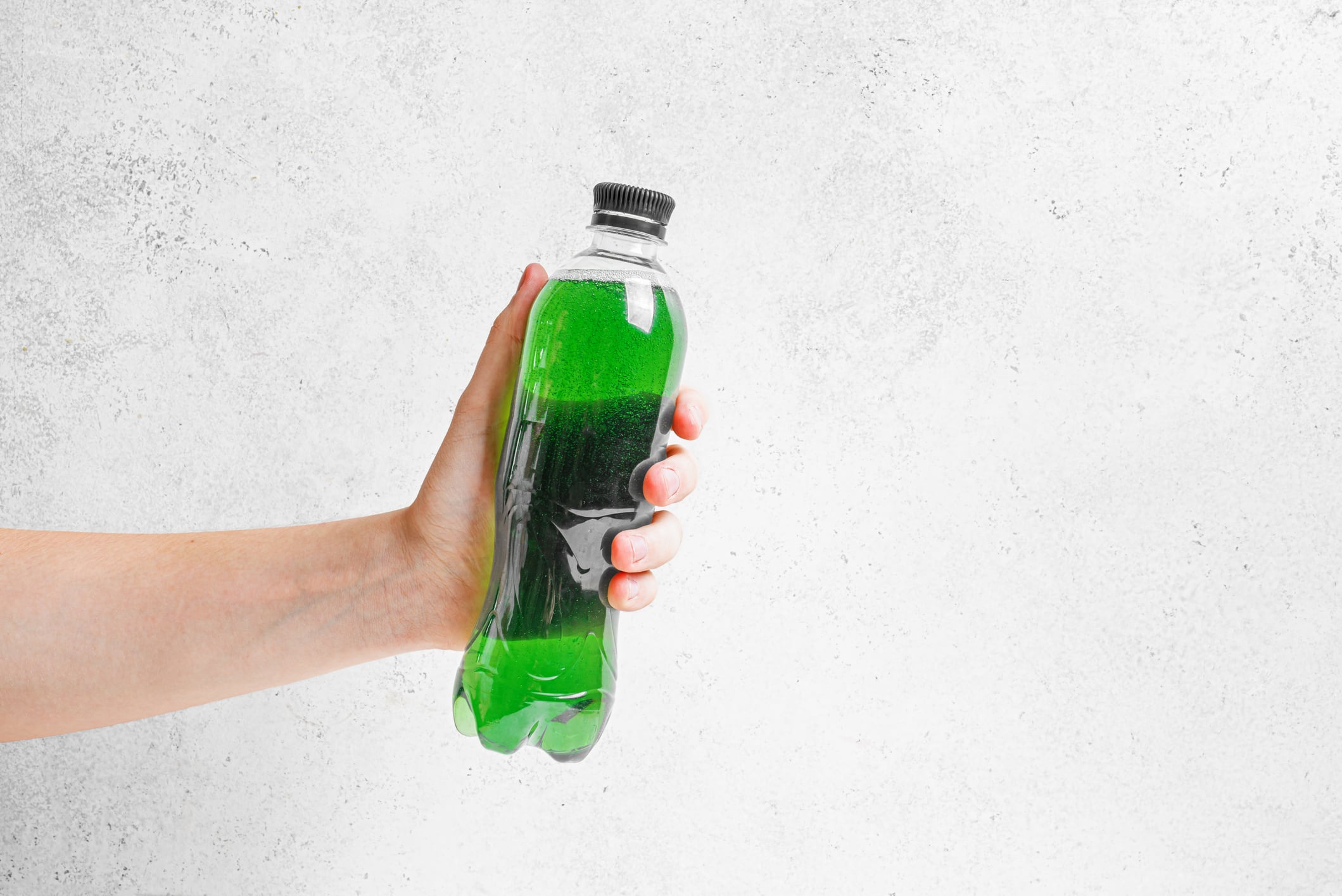 Liquid Green Chlorophyll Drink in hand. Man hold bottle of Chrorophyll Water on white background, copy space. Healthy fitness lifestyle, detox supplement concept template.