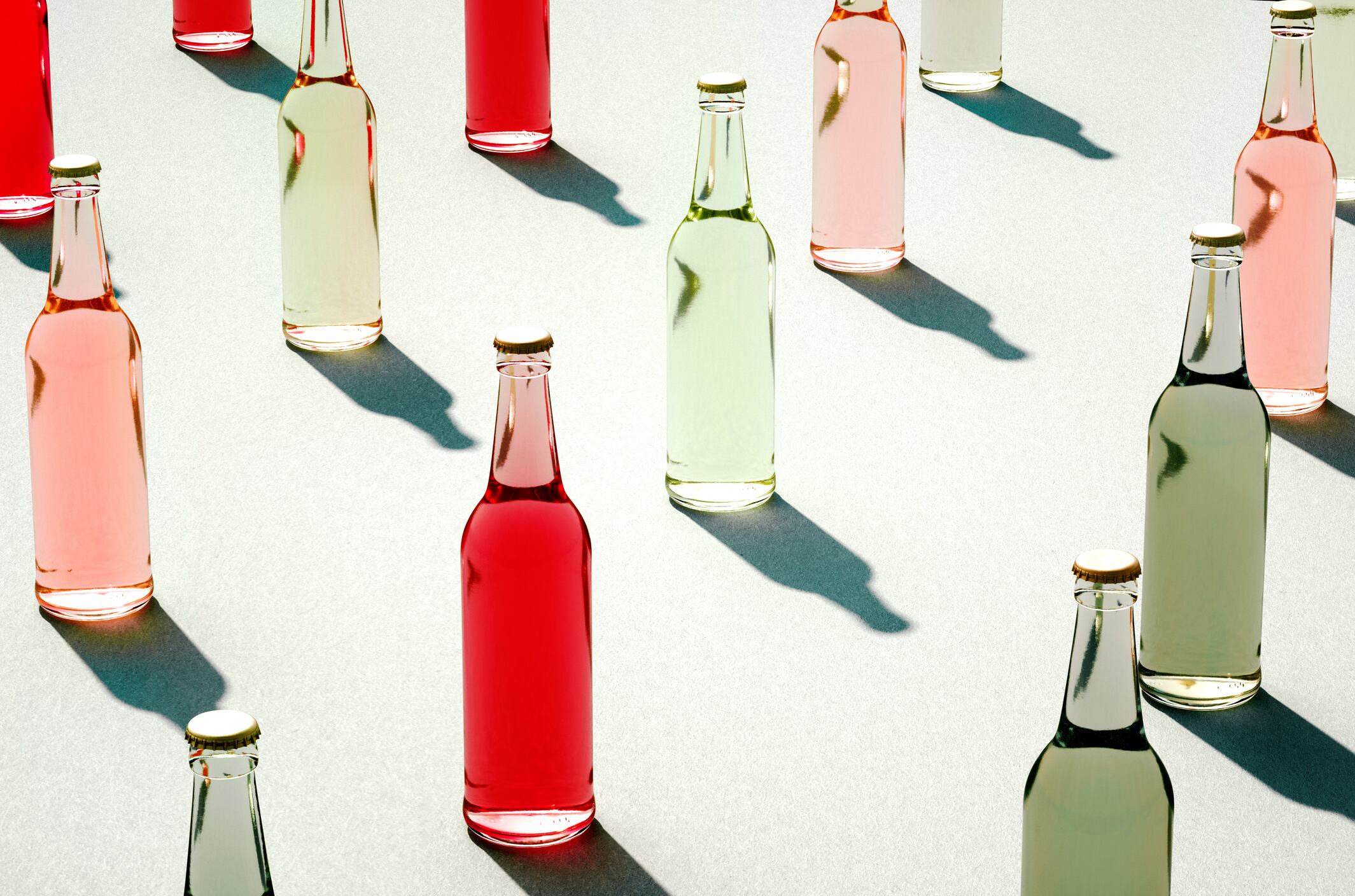 Various color glass bottles with shadows on white surface. 3d models of full and closed glass bottles without label. Retro drink bottle concept.