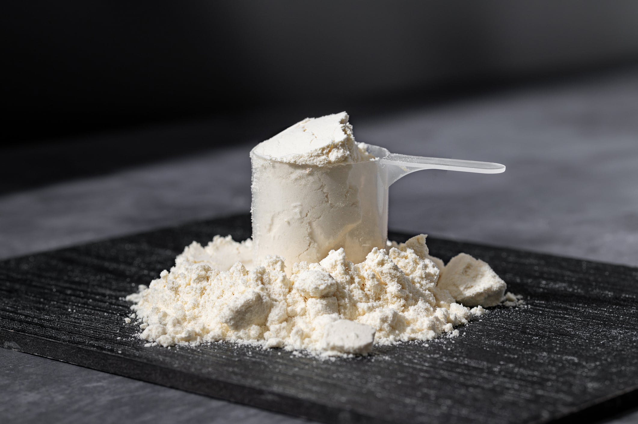 Protein powder in a scoop. Food supplements. Dark background. Bodybuilding, fitness, gym