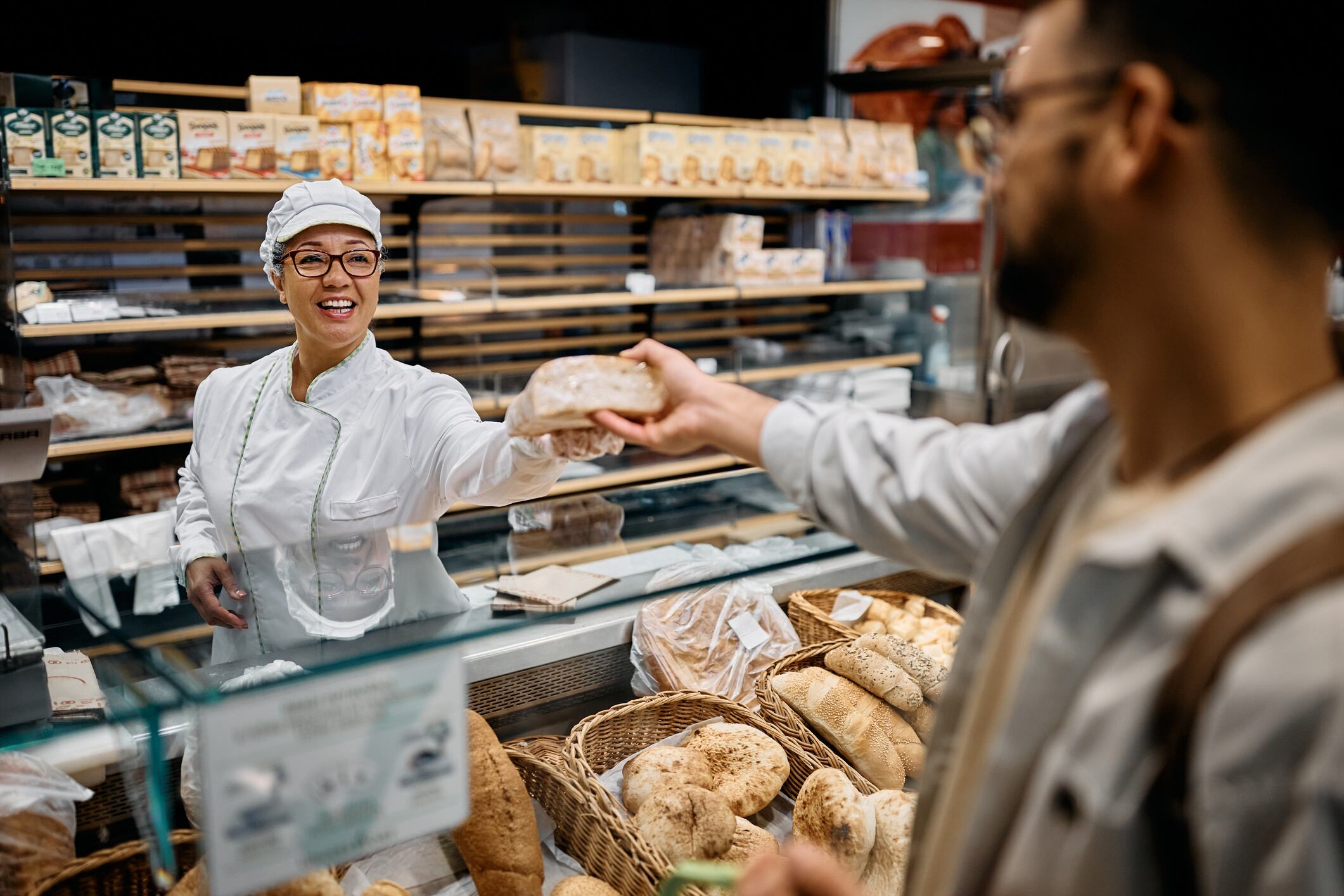 Happy supermarket baker serving male customer