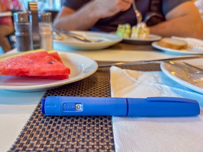 Ozempic semaglutide injection pen on restaurant table in front of person eating which is more hygienic toilet paper or bidet concept of diabetes medication, weight loss treatment, chronic disease.