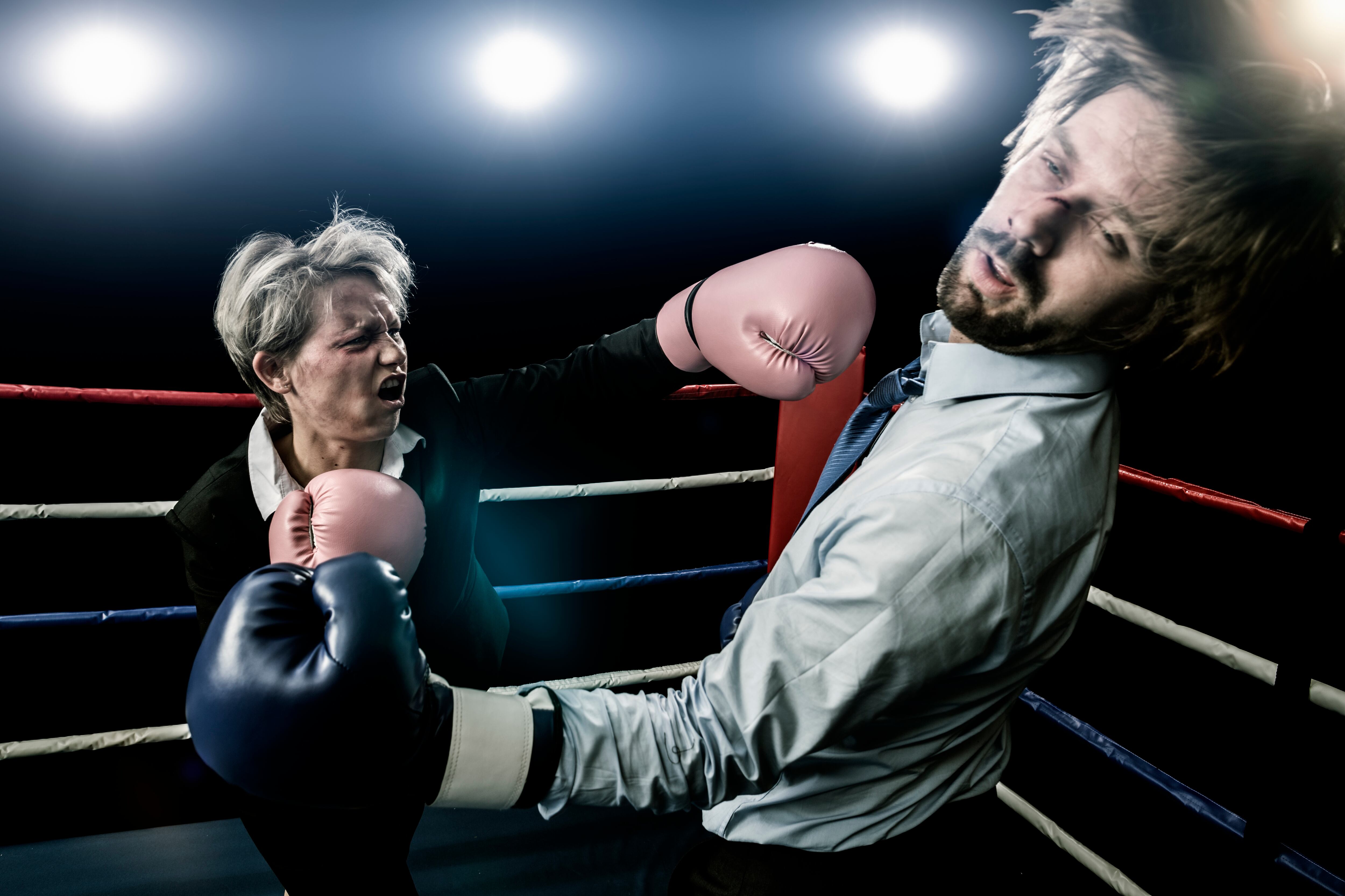 Fight between businesswoman and businessman in a boxing ring