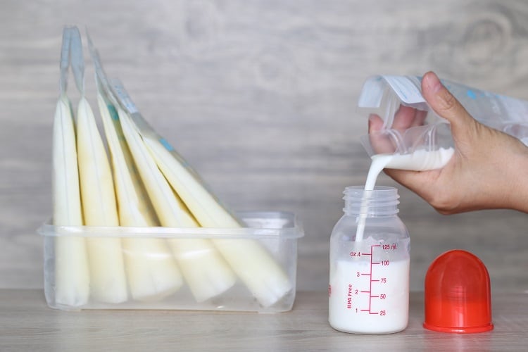 Breastmilk contains up to 15 times more osteopontin than cow's milk. Image: Woman pouring milk in to bottles for new baby on wooden table.