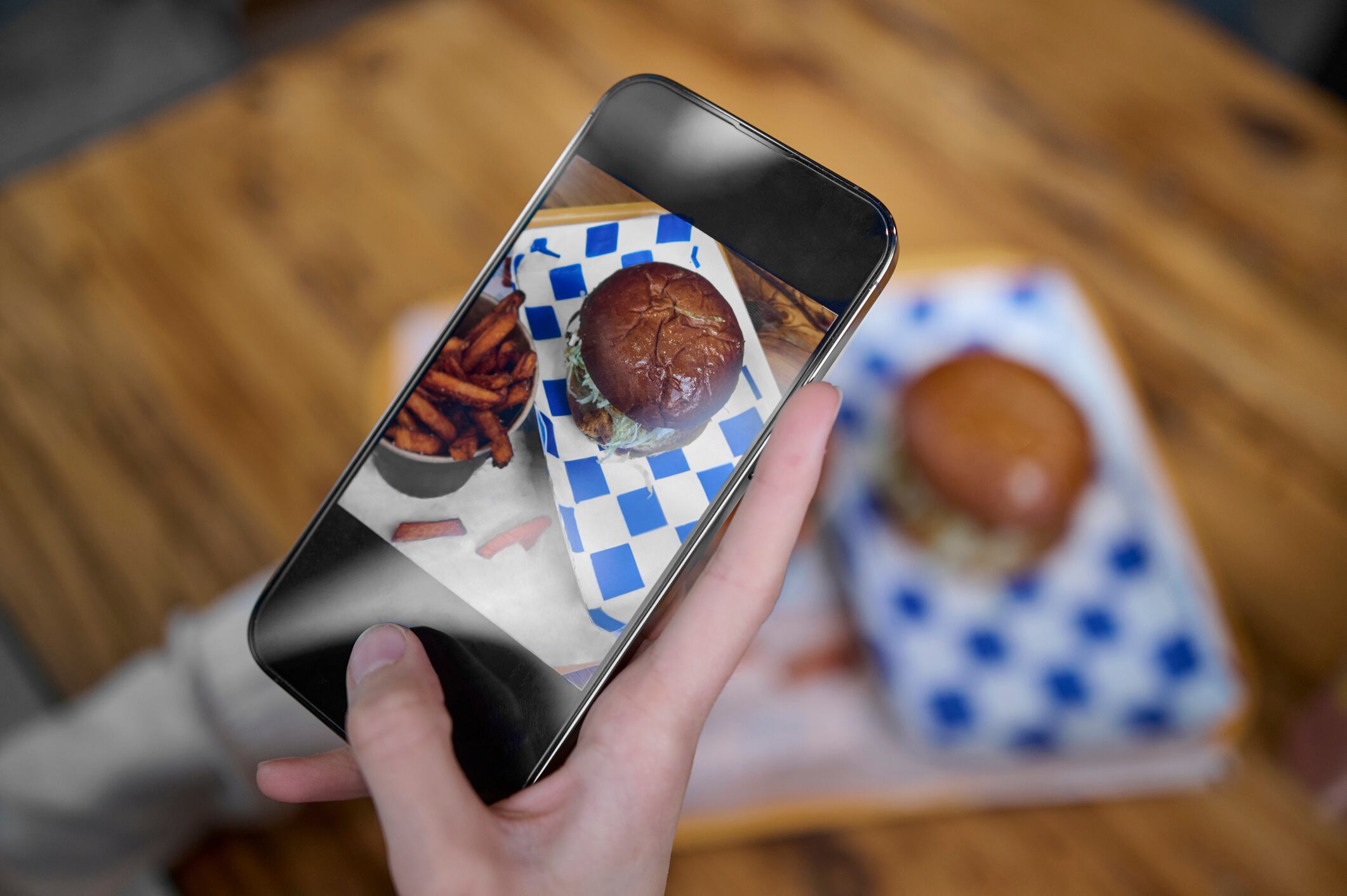 A phone taking a picture of a burger