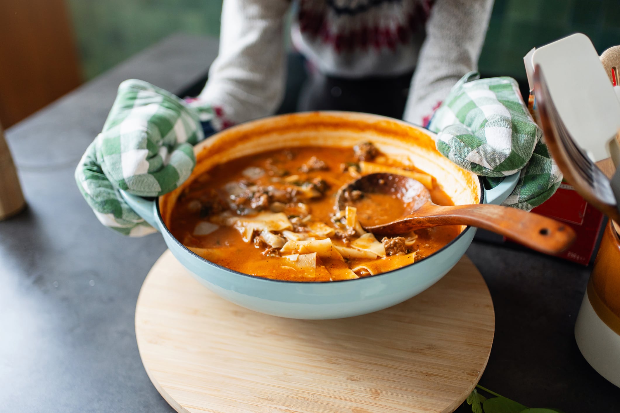 A warm bowl of delicious soup being presented in a cozy kitchen setting by a cook.