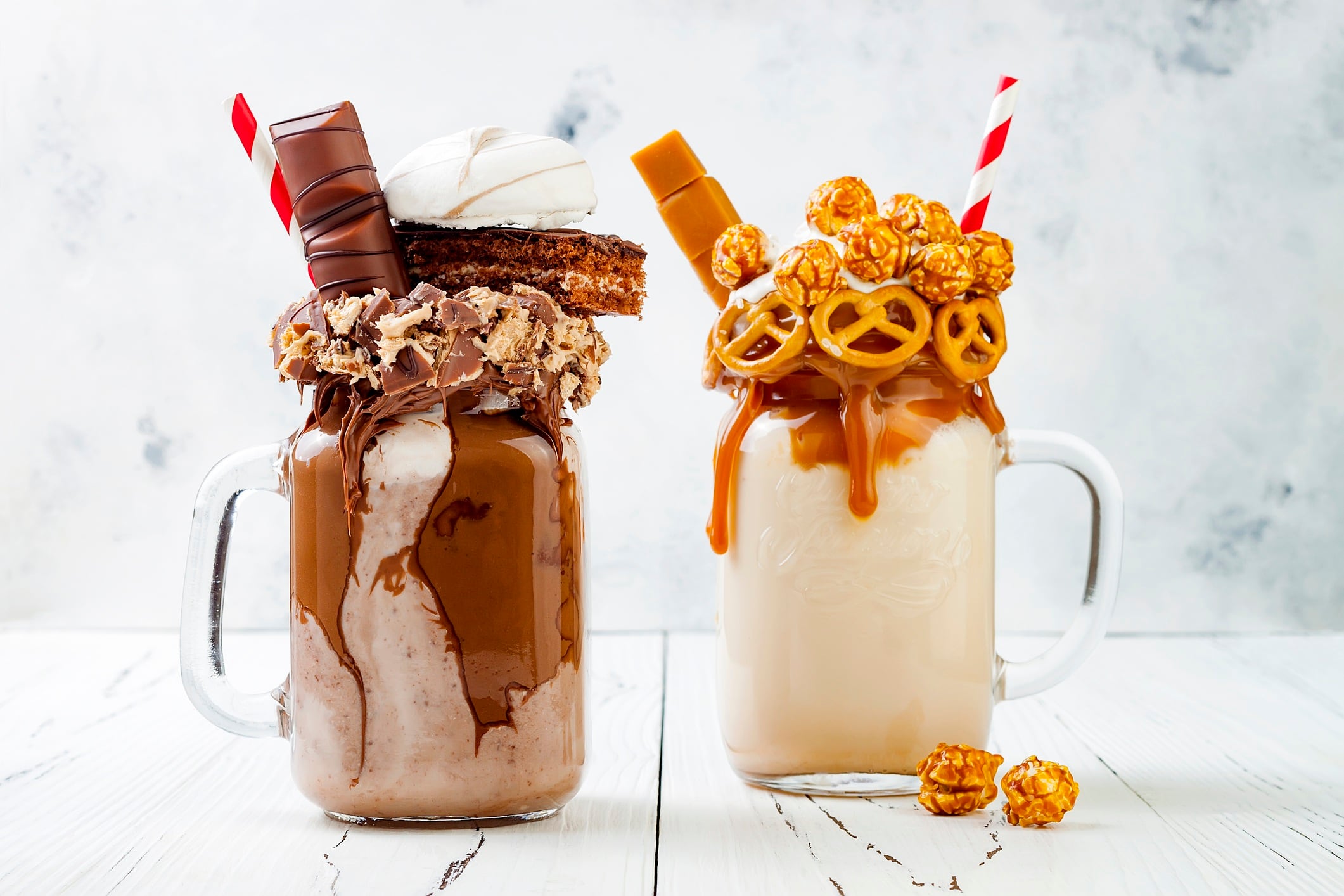 Caramel and chocolate indulgent extreme milkshakes with waffles, popcorn, marshmallows, ice cream and whipped cream. Freakshake food trend.