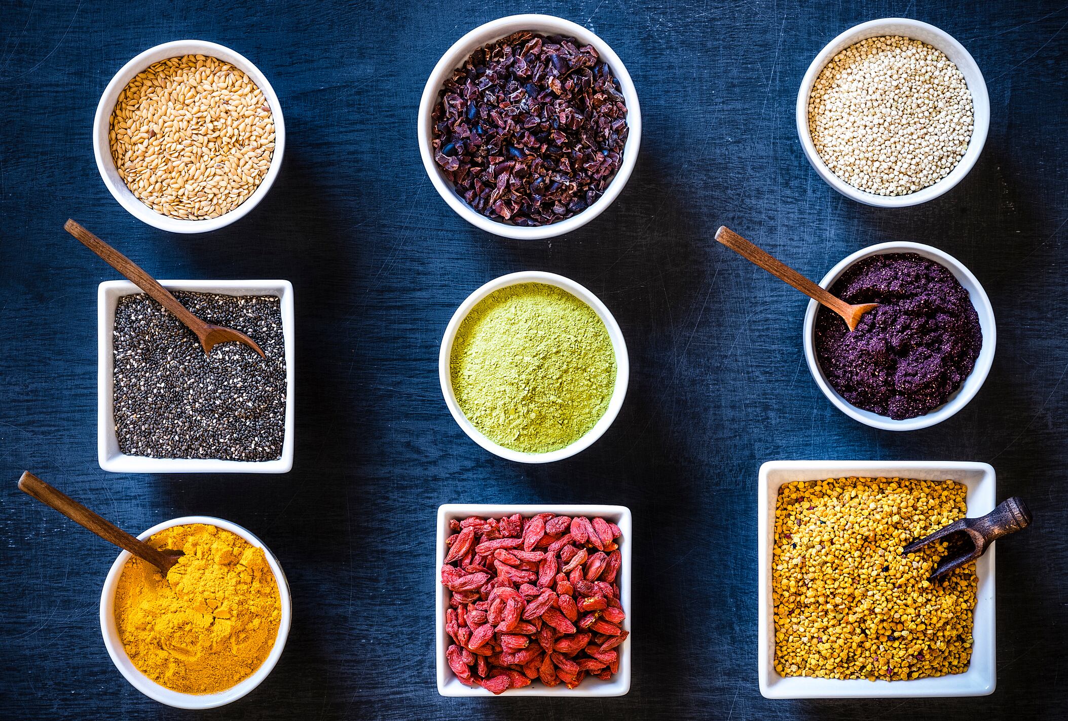 Top view of various bowls full of different types of superfoods.