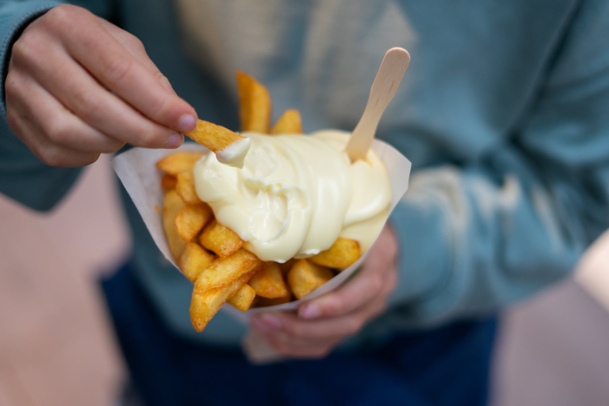 Child enjoying a cone of french fries dipped in mayonnaise, a popular street food