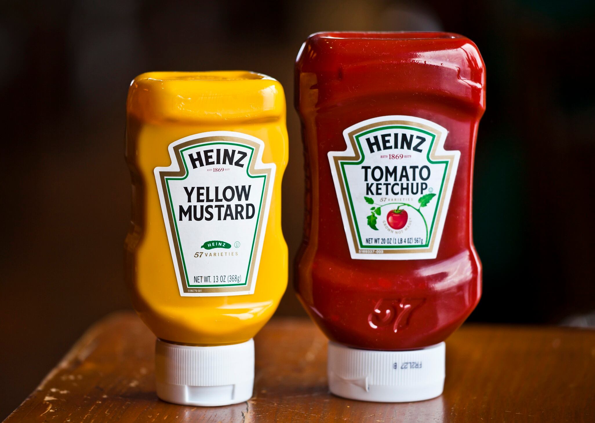 Plastic squeeze bottles of Heinz mustard and ketchup on wooden table in a fastfood restaurant in New York.