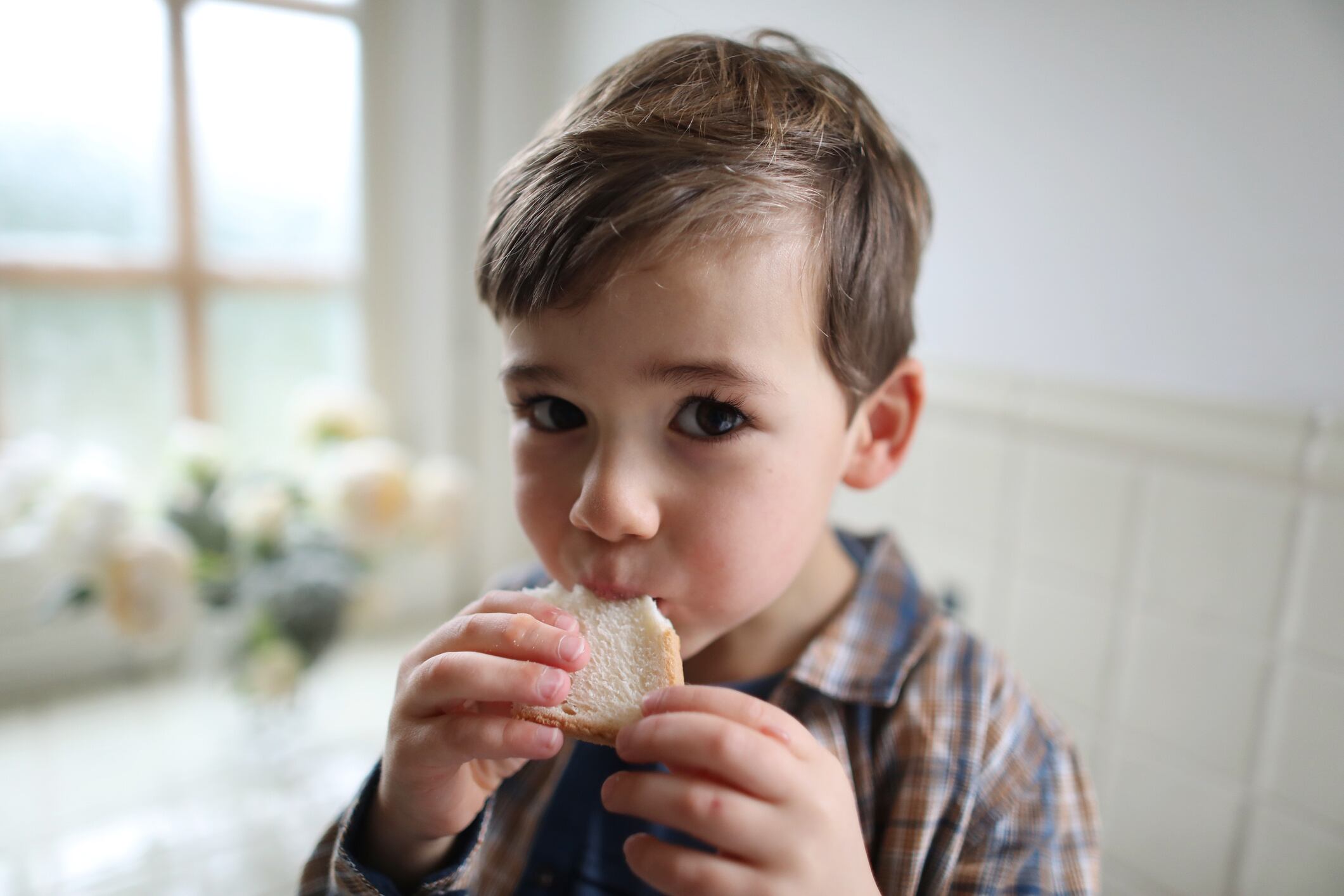 A four year old boy eating sliced bread in the kitchen Catherine Delahaye GettyImages