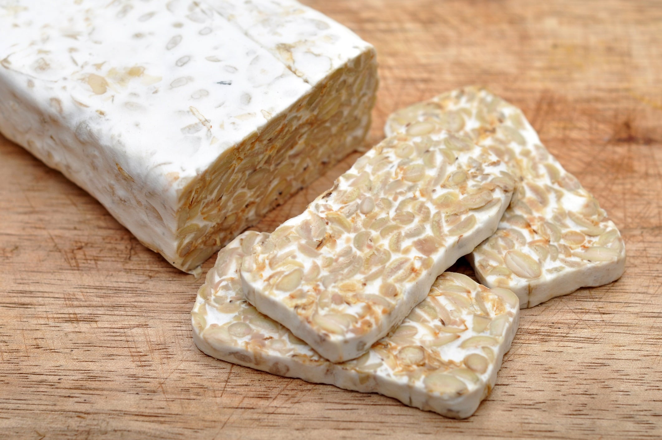 Sliced tempeh on wooden board.