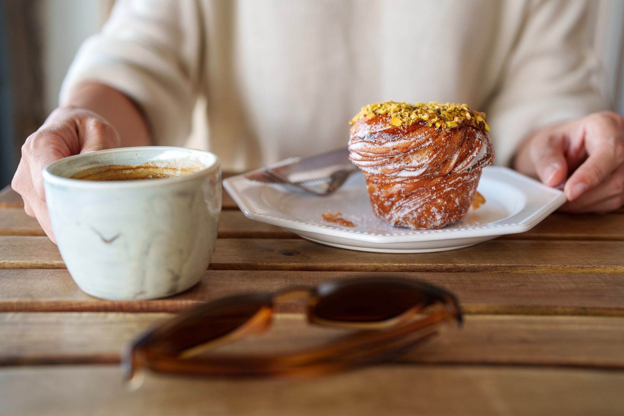 Cropped pic of woman eating cruffin with coffee