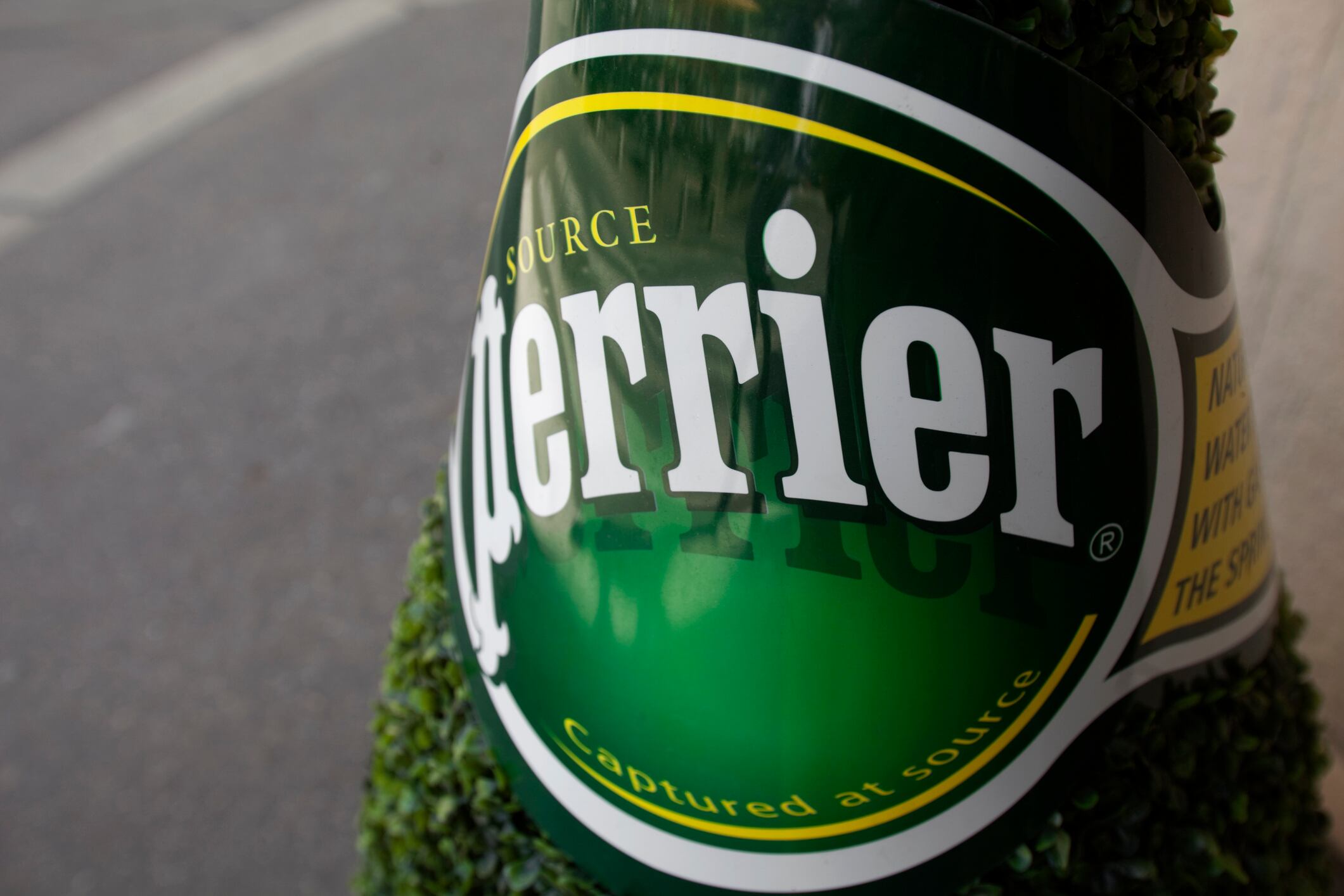 Rouen, Normandy, France - September 30 2011: Label of Perrier over a bottle-shaped hedge.