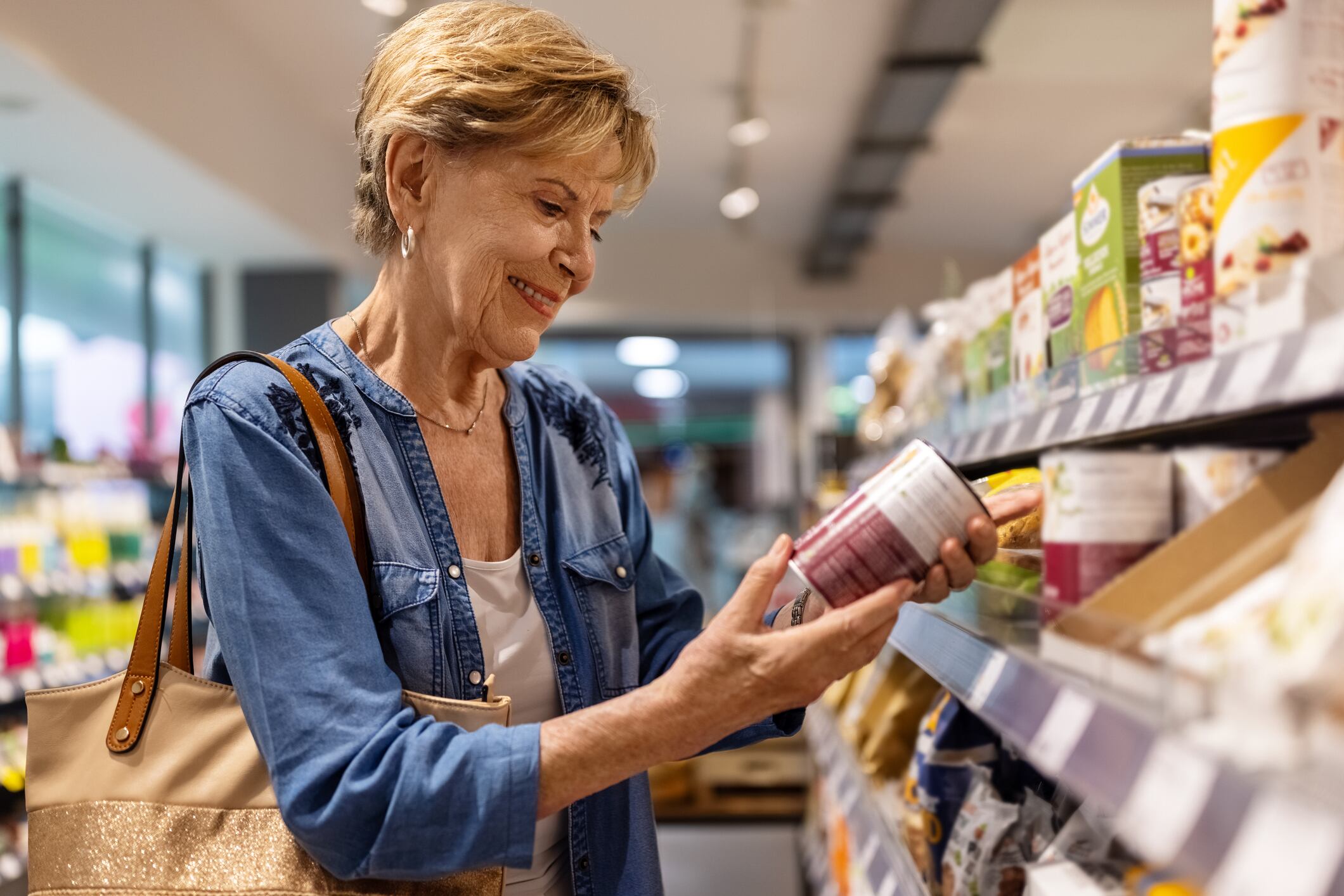 Senior woman in grocery store checking the product details. Mature female customer shopping grocery in a supermarket.