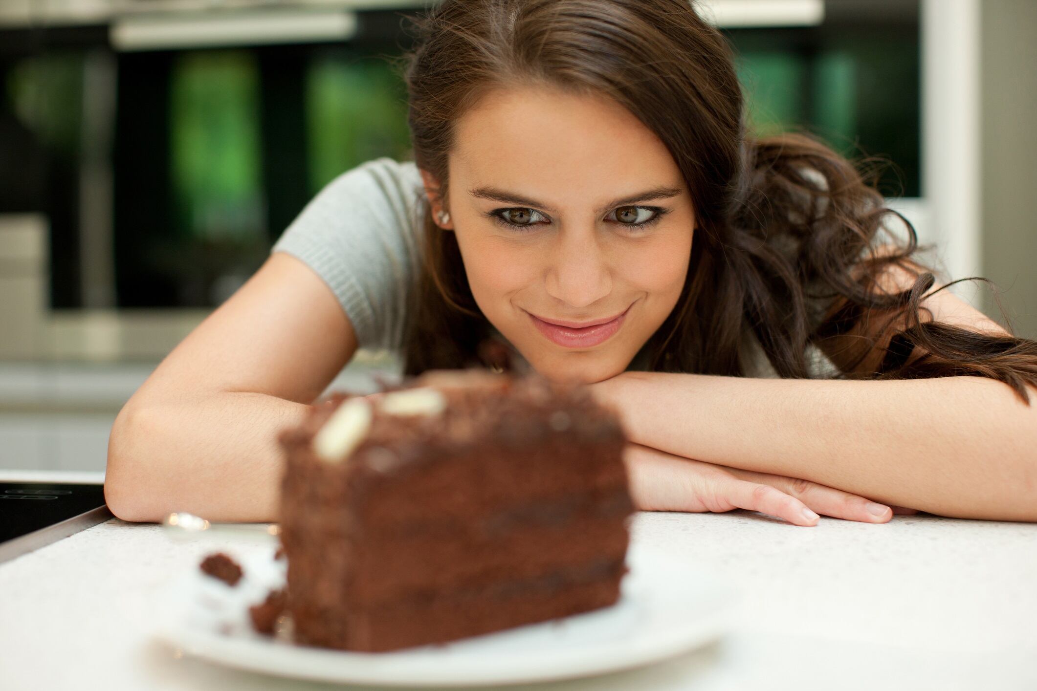Woman staring at chocolate cake and smiling.