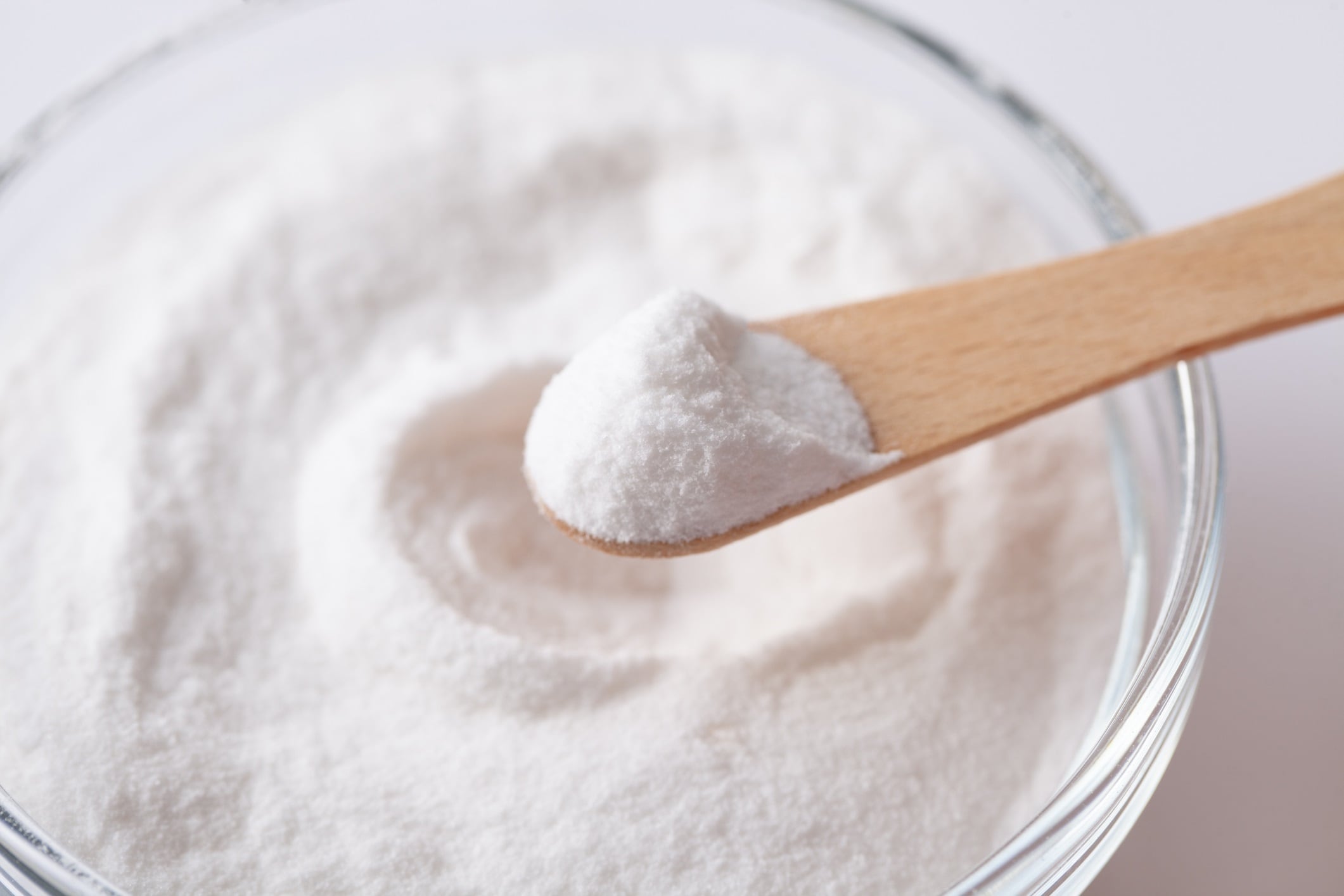 Chemical powder on a wooden spoon aspartame E951 over a bowl