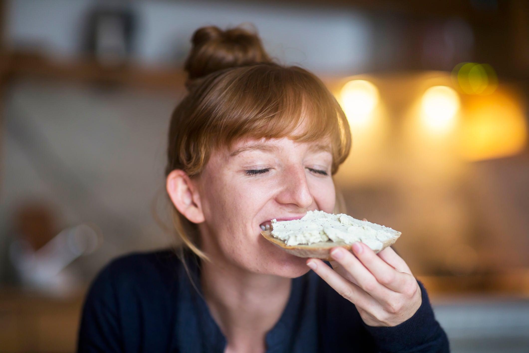 Woman eating cheese on bread.