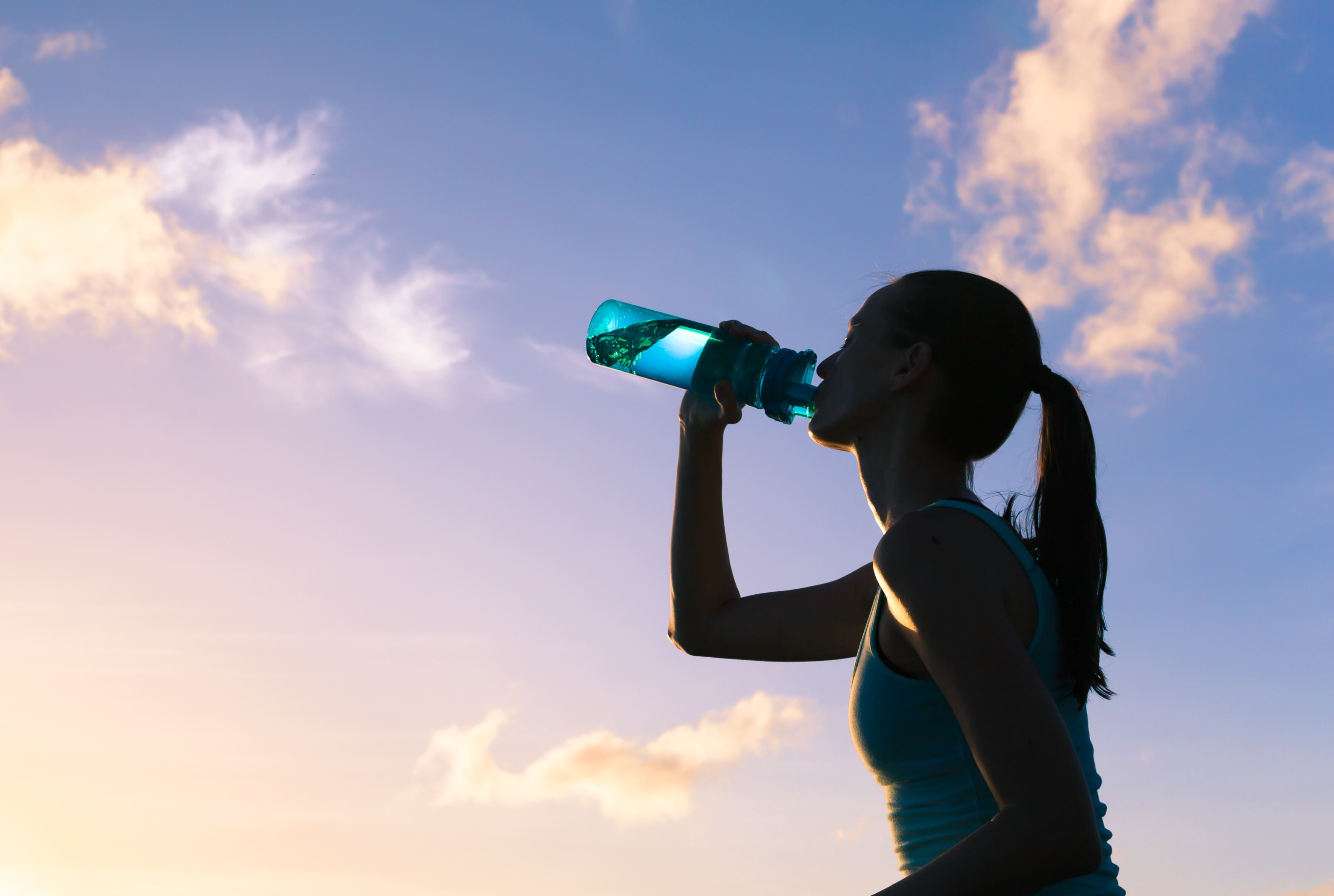 Woman drinking water in a hot summer day.
