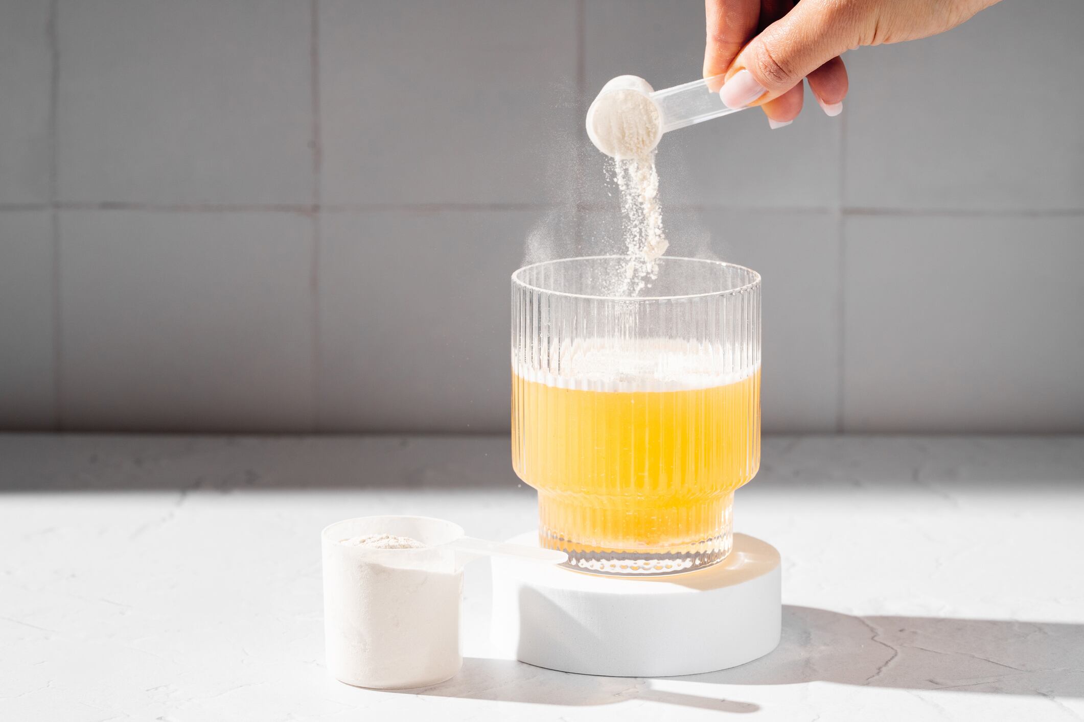 The collagen market is predicted to grow. Collagen protein powder in a scoop. Glass of collagen beauty drink. Food supplement.