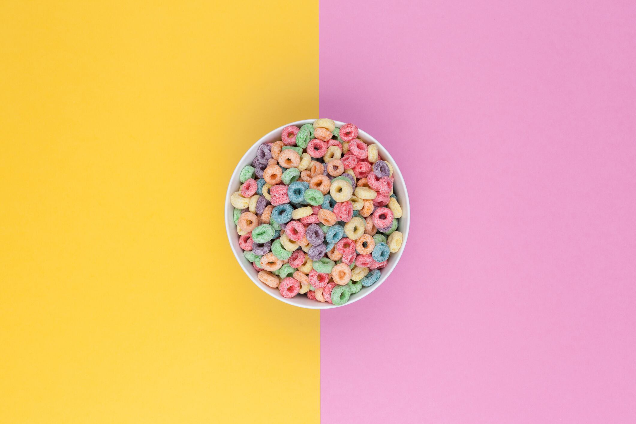 Bowl of colorful cereals top view and two colored background