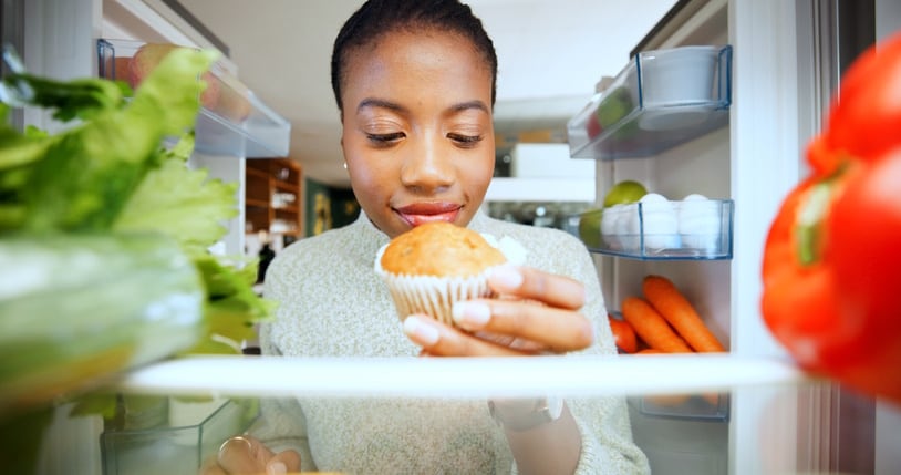 Kitchen, fridge and black woman with muffin, pov and home with nutrition, hungry and option. African person, apartment and refrigerator with dessert decision, sweet craving and healthy diet break Jacob Wackerhausen GettyImages