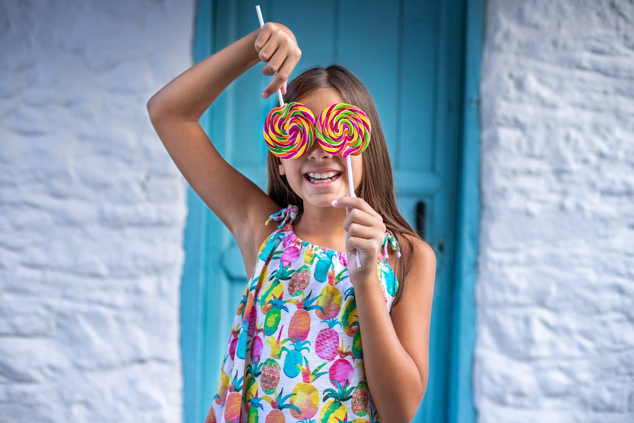 Young girl holding spiral lollipops over eyes.