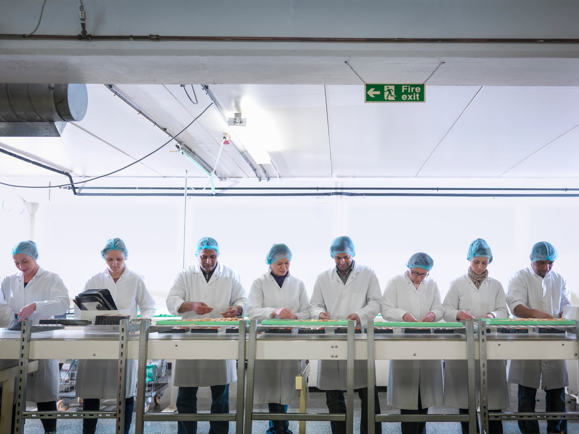 Workers packing chocolates on production line in chocolate factory