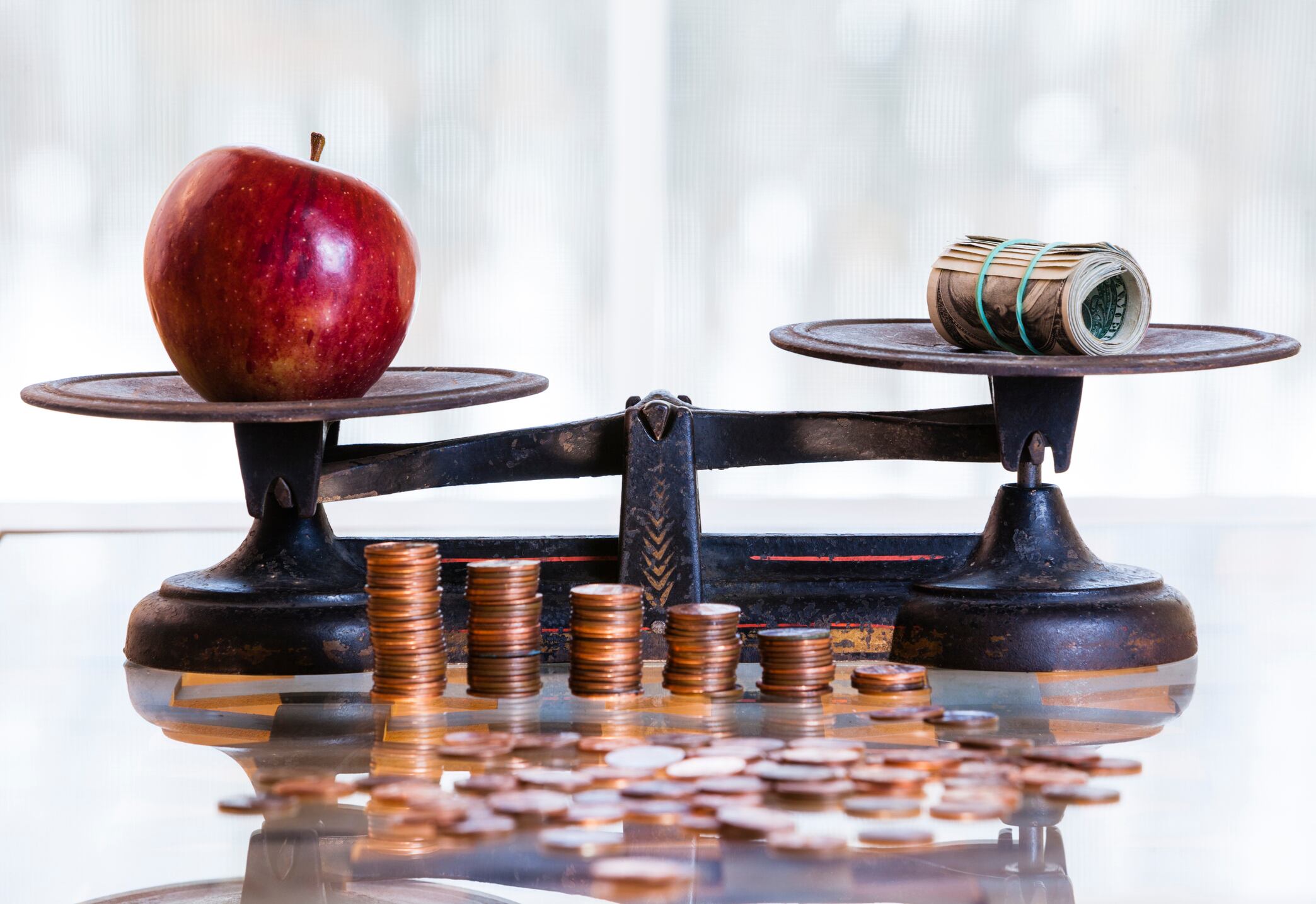 dollars and apple on the antique scales, Piles of coins at front of scales.