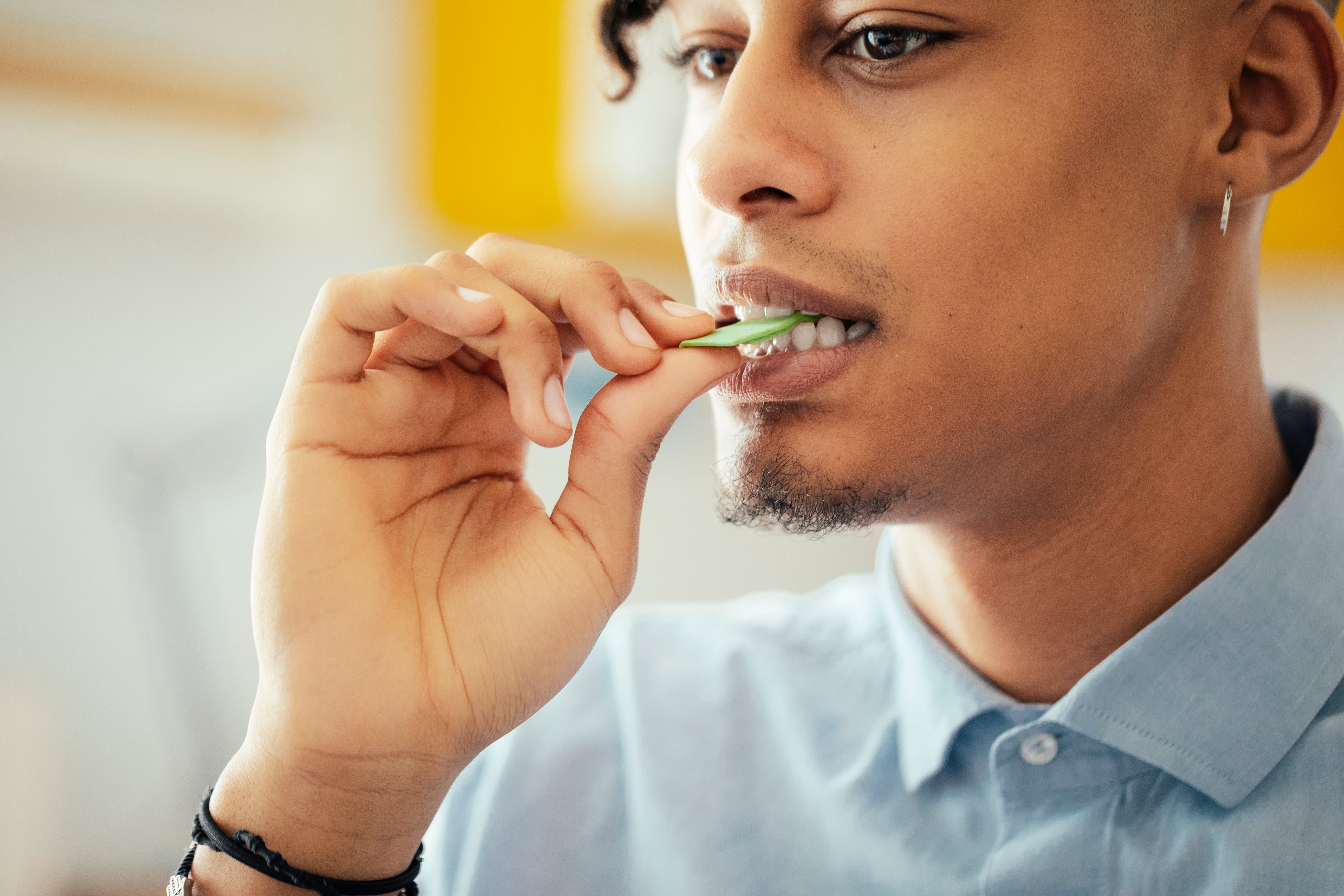 A young man putting a piece of chewing gum in his mouth.