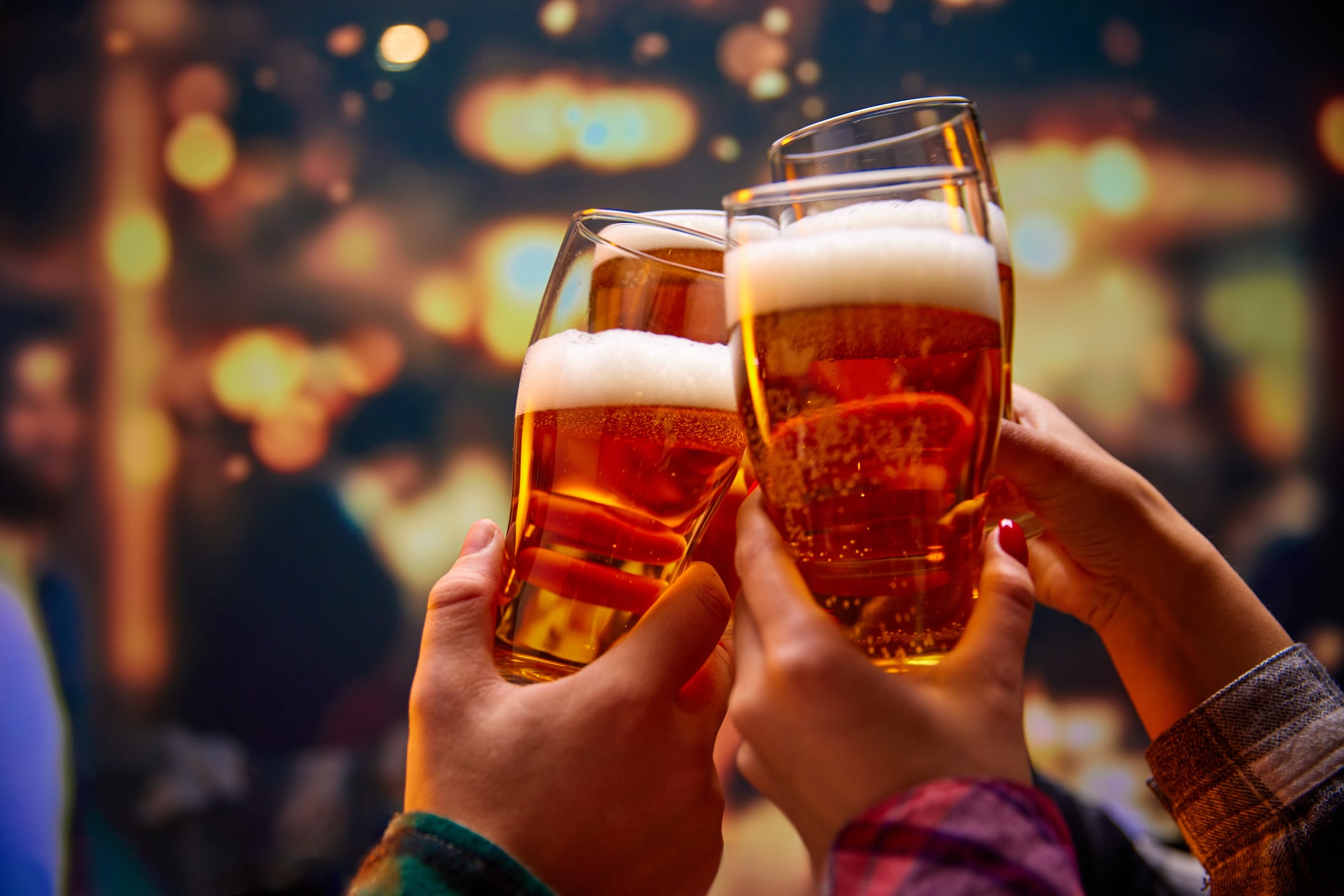 Close up shot of unrecognizable group of friends saying toasts and drinking beer and clinking glasses in bar while watching match. Concept of Beer Fest, party, celebration, national traditions.