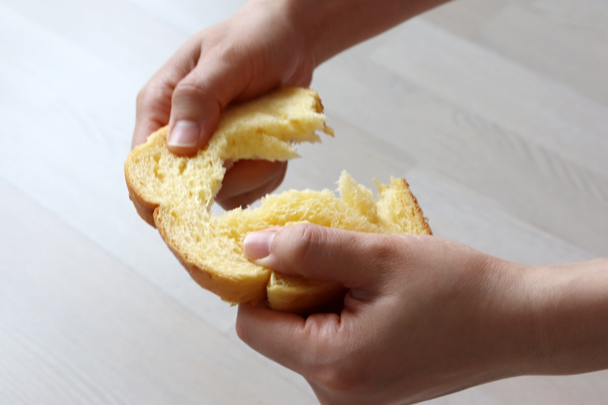 Hands tearing a piece of brioche